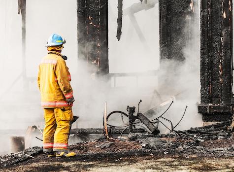 Firefighter investigates the devastation of a house fire - Image